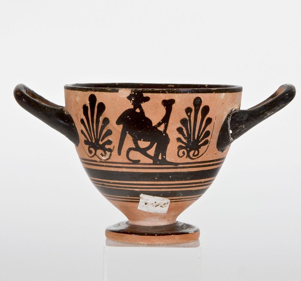 Coppa (skyphos) in ceramica attica a figure nere raffigurante Dioniso seduto con in mano un rhyton,